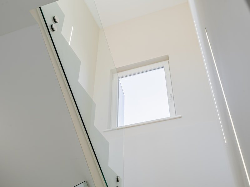 A frameless glass railing panel on a modern staircase